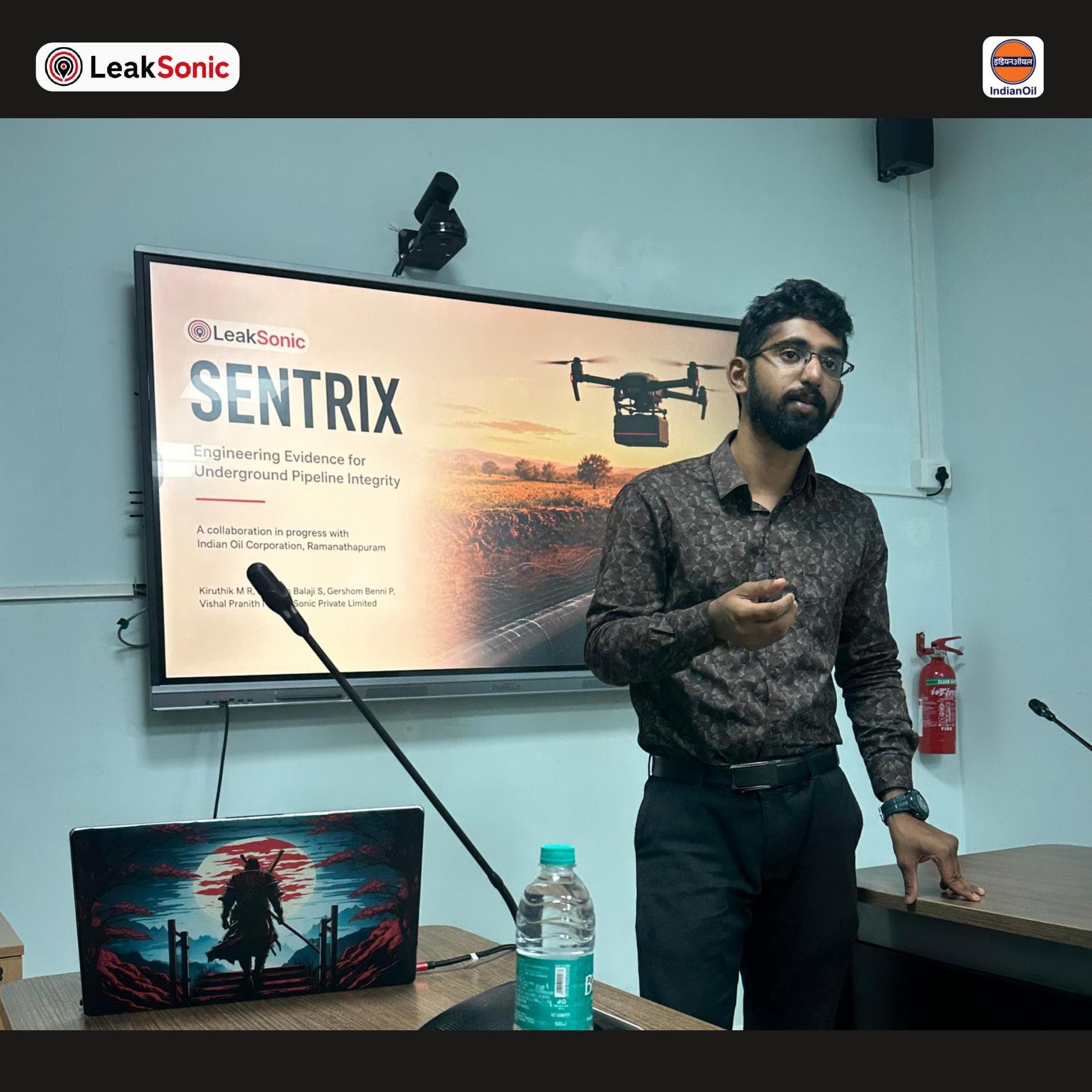 A LeakSonic team member presenting the Sentrix title slide, Engineering Evidence for Underground Pipeline Integrity, a collaboration in progress with Indian Oil Corporation, Ramanathapuram, on a large display screen